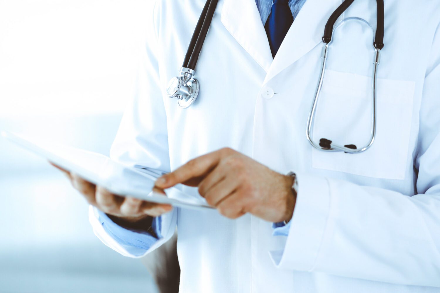 Doctor man using tablet computer for network research or virtual disease treatment, hands close-up. Perfect medical service in clinic. Modern medicine, medic data and healthcare concepts. Toned picture