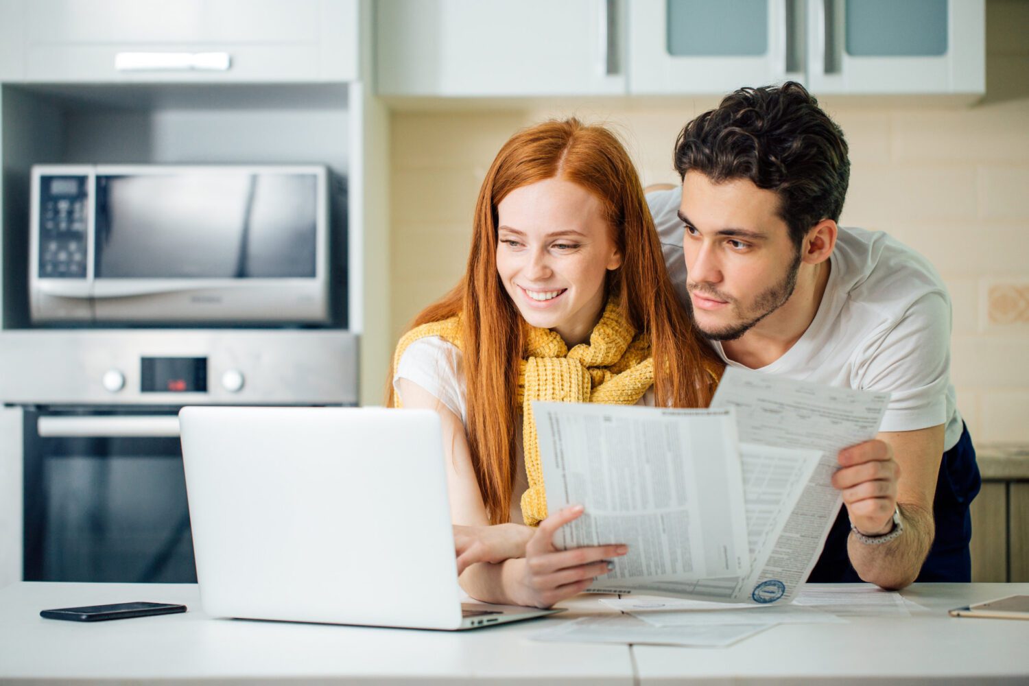 cheerful young couple calculating their bills at home